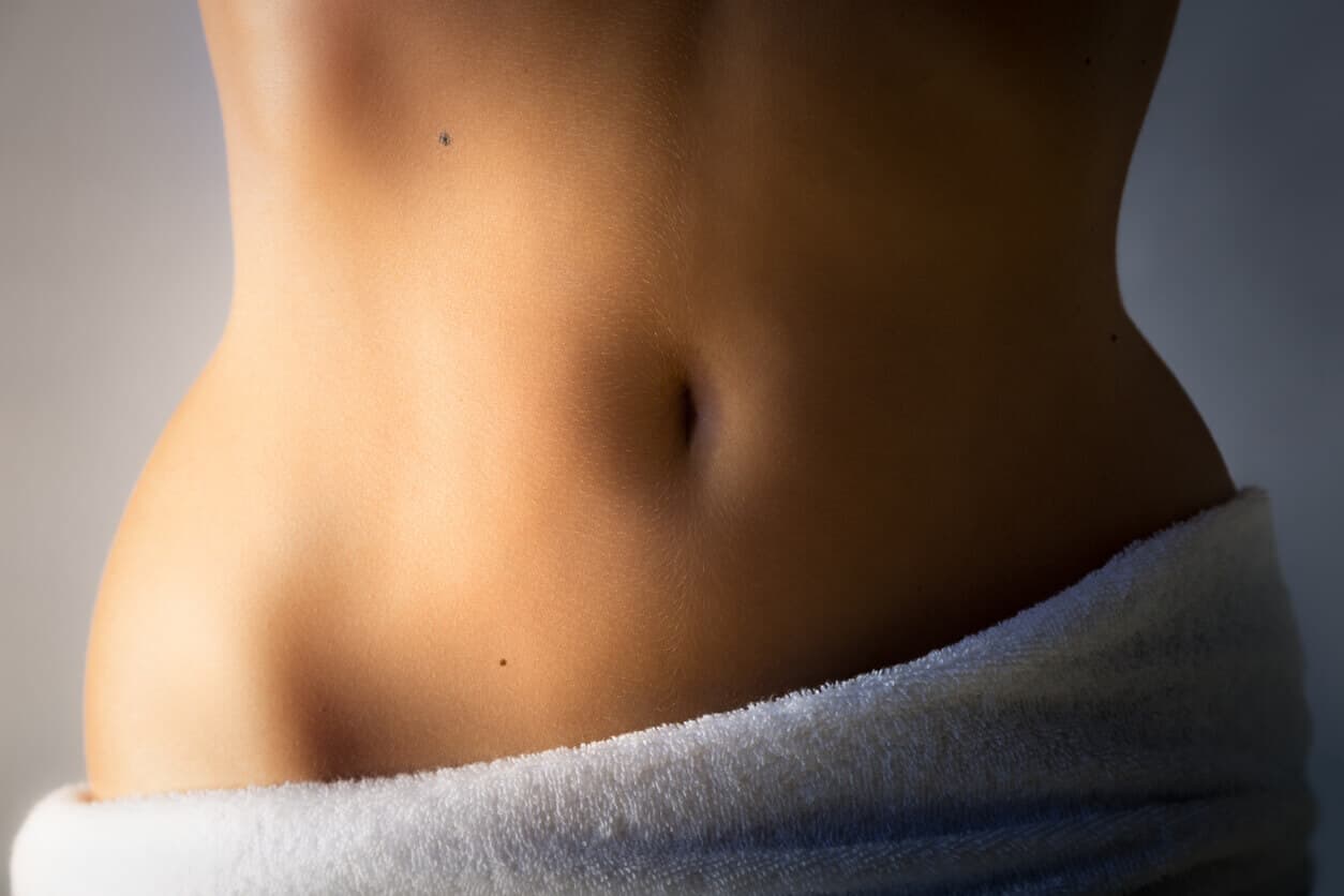 Close na região abdominal de uma mulher, evidenciando o umbigo e a pele lisa, representando resultados estéticos de abdominoplastia sem mexer no umbigo