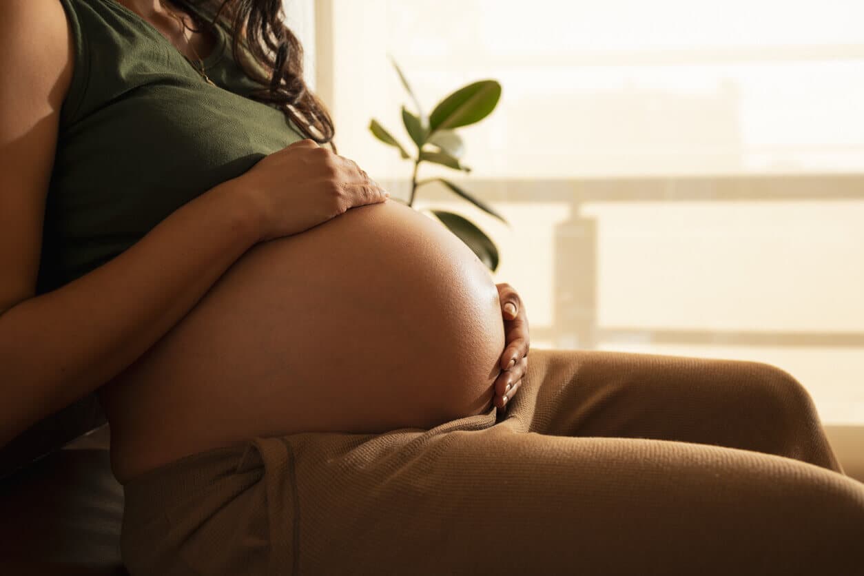 Mulher grávida sentada, com a barriga exposta