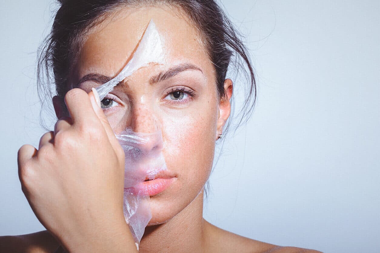 Mulher remova camada de descamação após realizar peeling facial